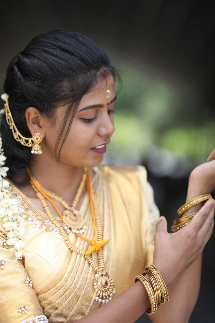 Guruvayur wedding makeup - bride in gold saree adjusting bangles