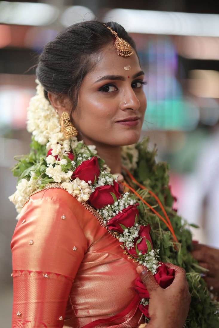 Guruvayur bridal makeup - bride in orange silk saree with rose and tulasi garland