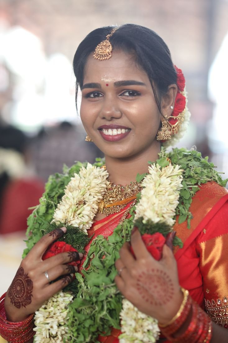 Bridal makeup near Guruvayur temple - smiling bride in red saree with mehndi and flower garland
