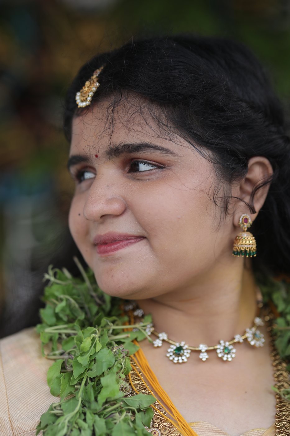 Guruvayur bridal makeup - bride in profile with maang tikka, jhumka and tulasi garland