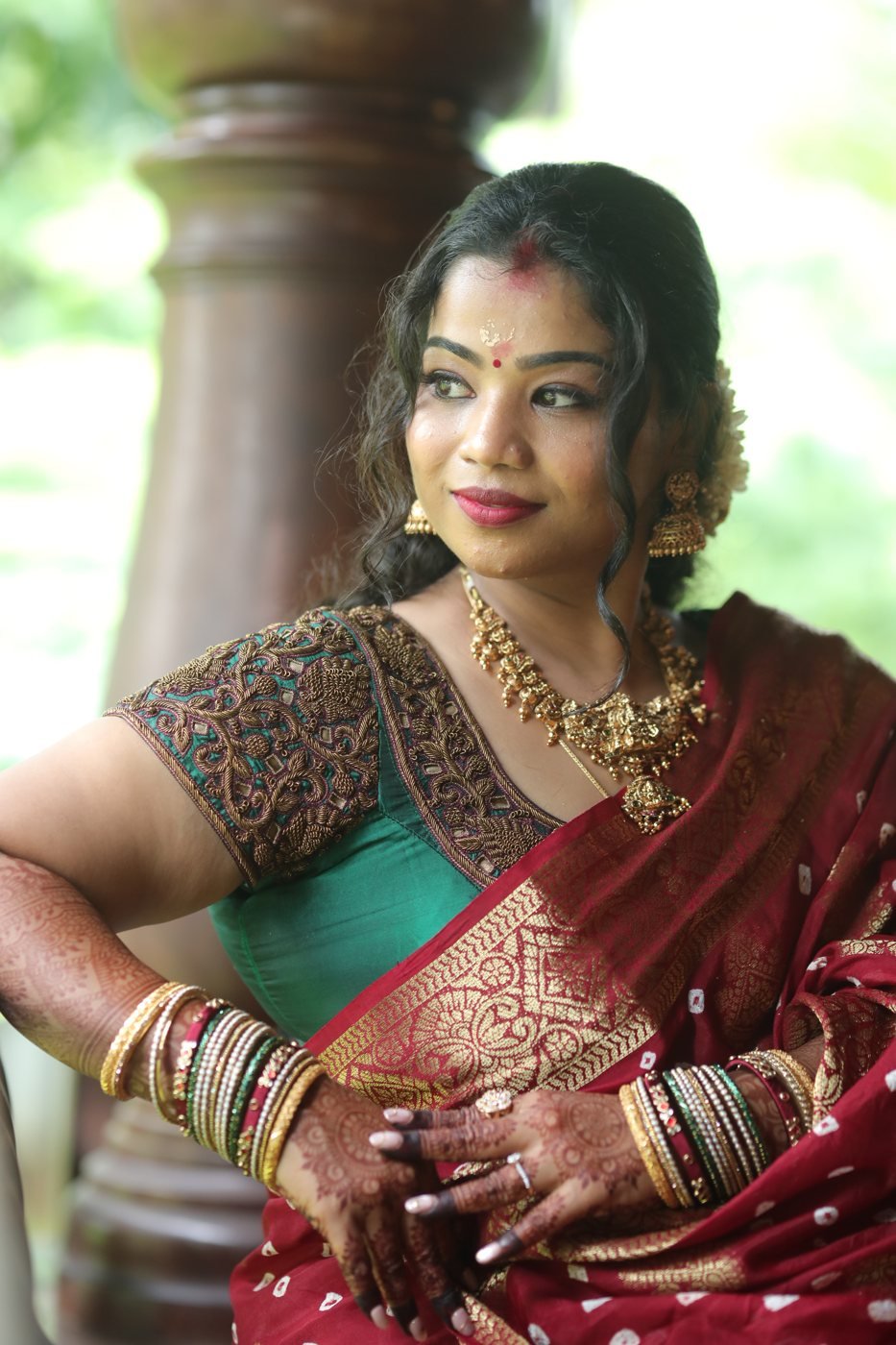 Guest look makeup package Guruvayur - woman in maroon bandhani saree with mehndi and bangles